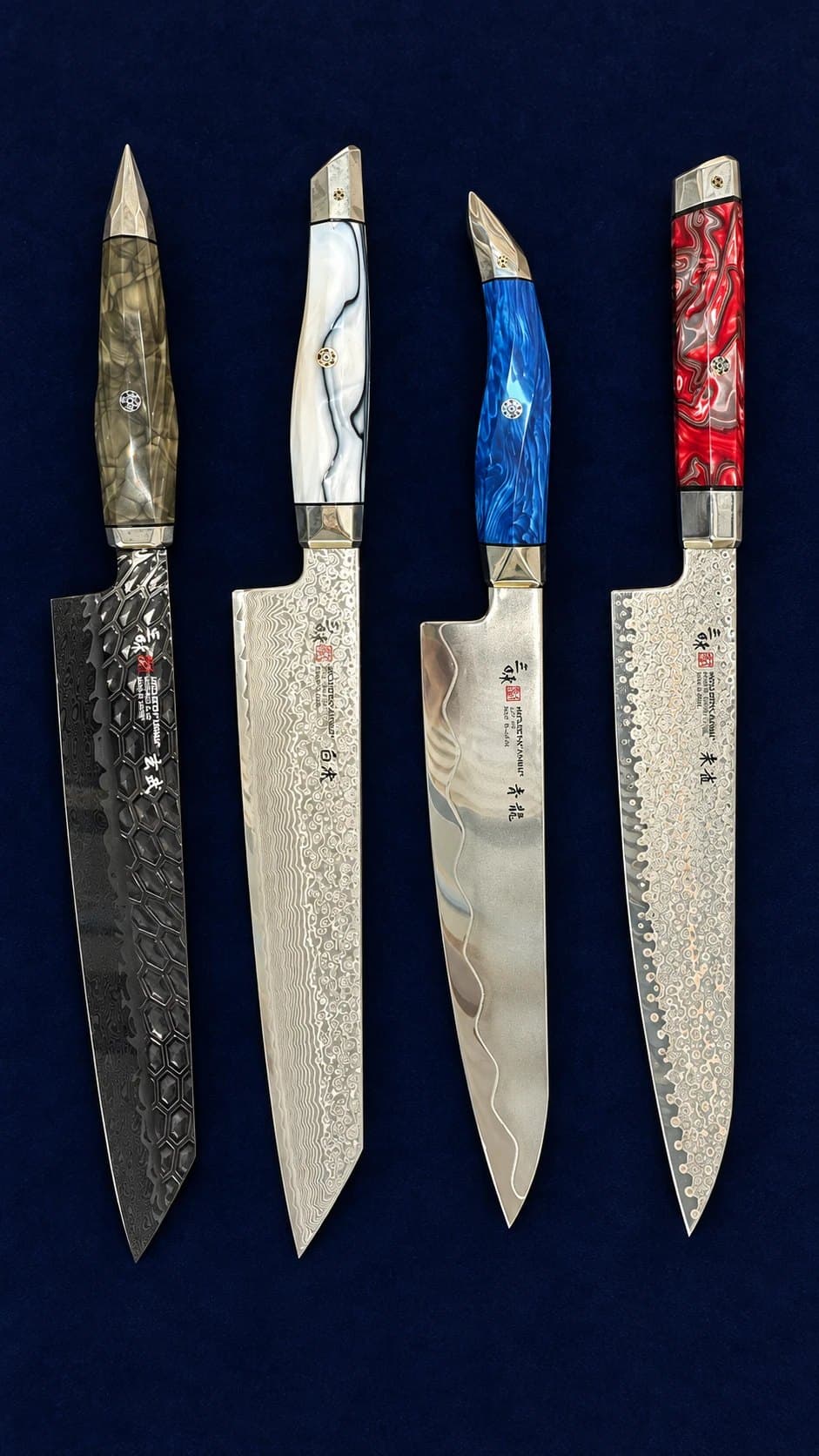Four Damascus-pattern Japanese knives with resin handles laid on dark blue cloth