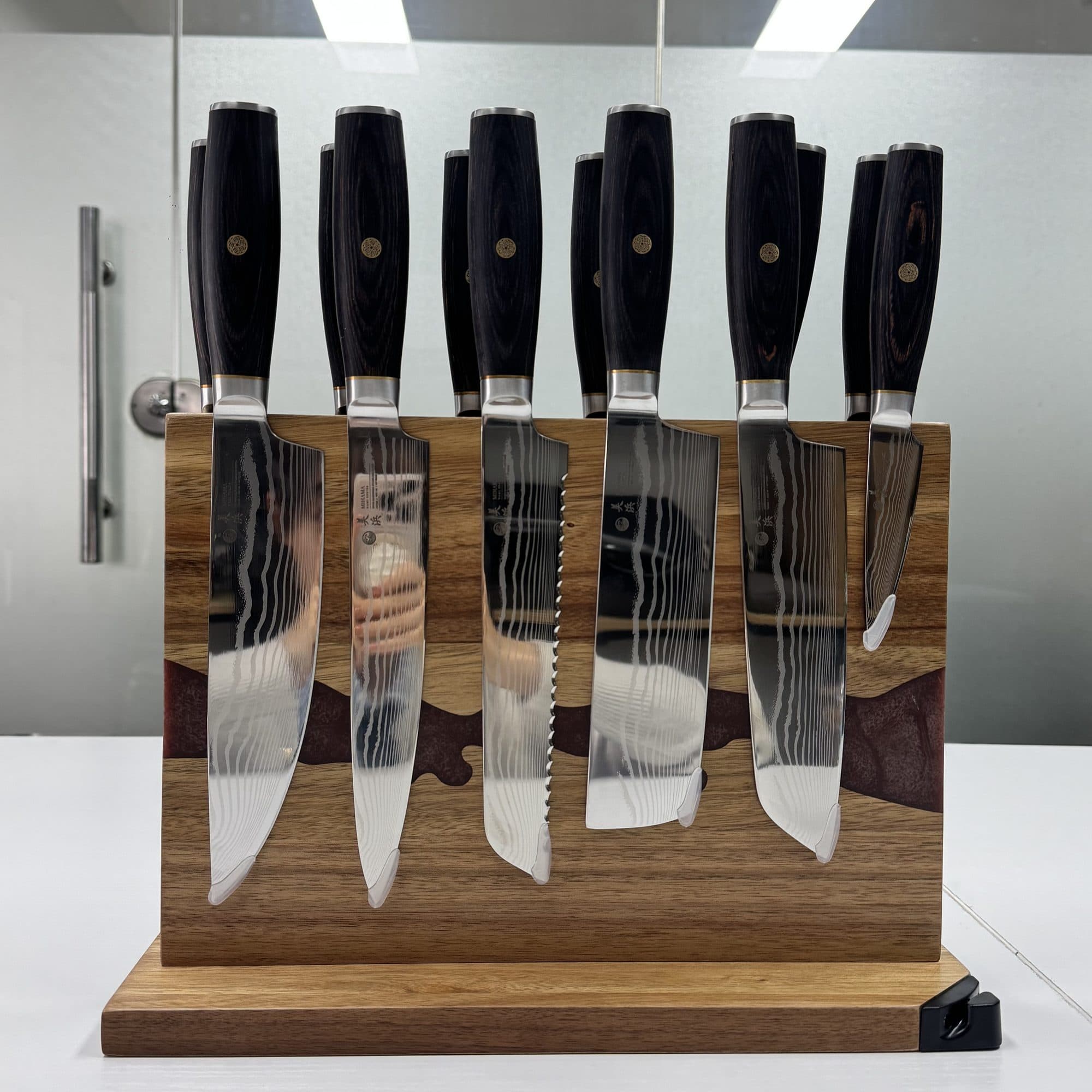 Six knives held on the magnetic stand, the stone-vein inlay running through the wood