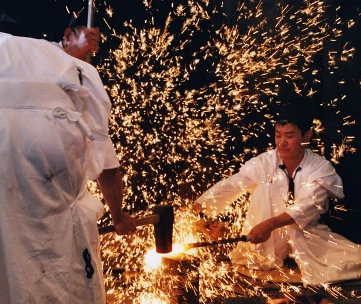 Two swordsmiths in white hammering glowing steel, sparks filling the air