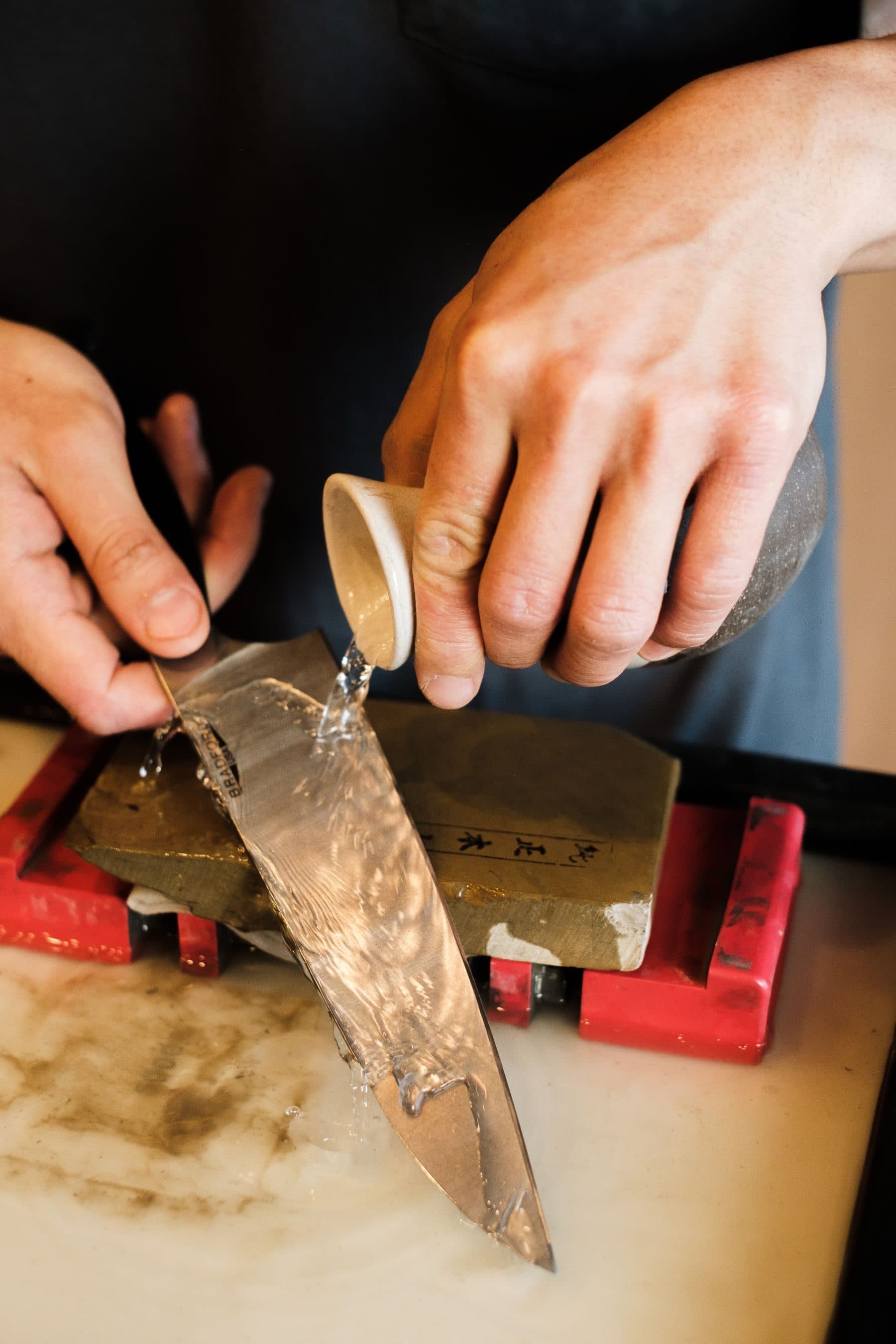 Pouring water over a whetstone before sharpening a knife